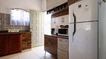 A kitchen with a refrigerator, microwave, and a coffee maker on the counter.