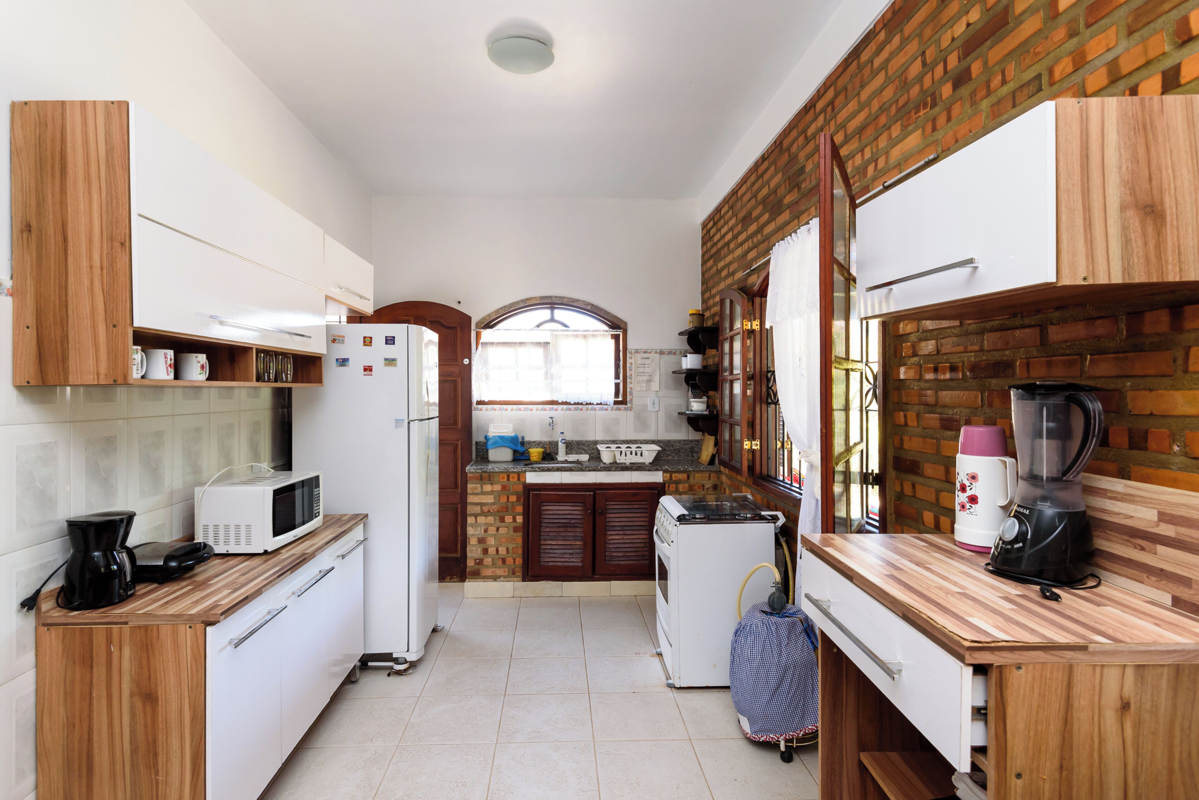 Una cocina compacta con electrodomésticos blancos, armarios de madera y una pared de ladrillo.