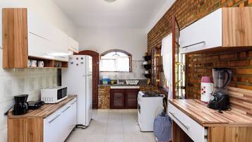 Una cocina compacta con electrodomésticos blancos, armarios de madera y una pared de ladrillo.