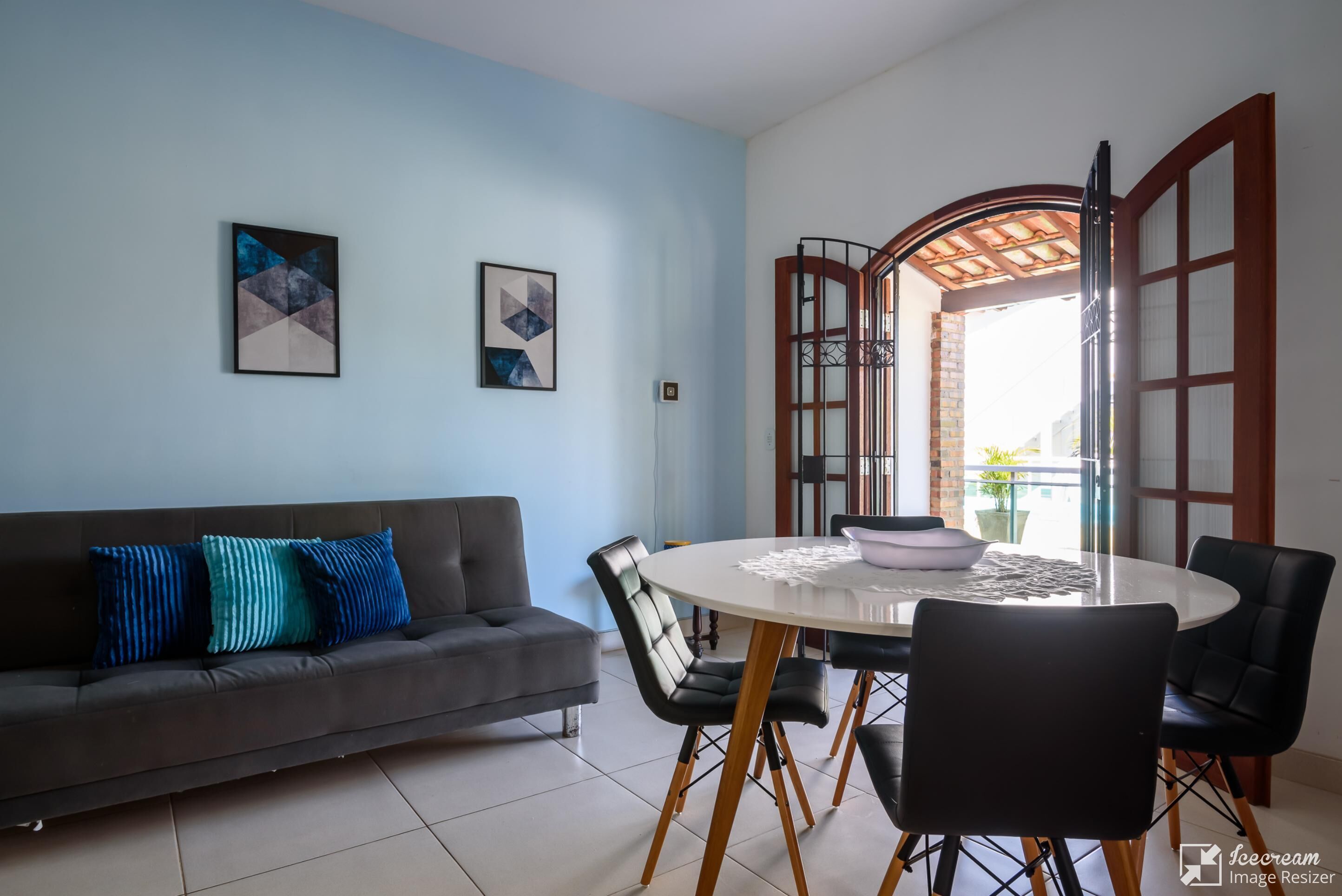 Ein Wohnzimmer mit einer Couch, einem runden Esstisch mit Stühlen und einem großen Fenster mit Ausblick.