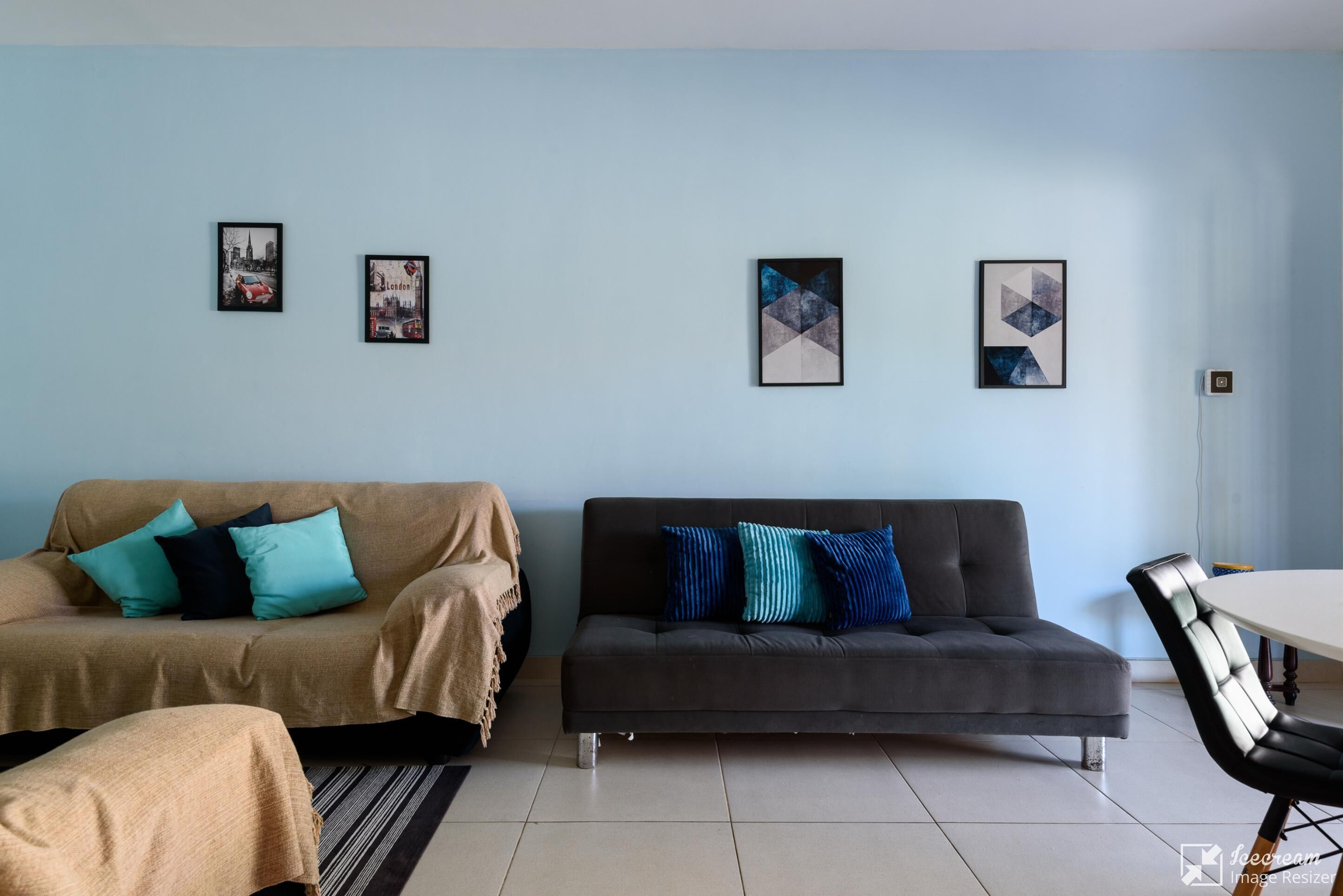 A living room with two sofas, a coffee table, and a dining table. There are framed pictures on the wall.