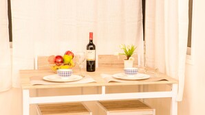 Een eettafel met een fruitschaal, een fles wijn en een kleine plant.
