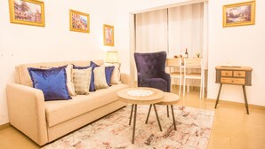Een woonkamer met een bank, fauteuils, een salontafel en een eethoek met een tafel en stoelen.