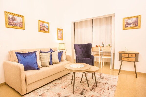 Uma sala de estar com sofá, poltronas, mesa de centro e um espaço de jantar com mesa e cadeiras.