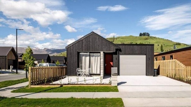 A modern single-story house with a garage, a small front yard with a white chair, and a wooden fence. - NV Homes (Lake Hayes)
