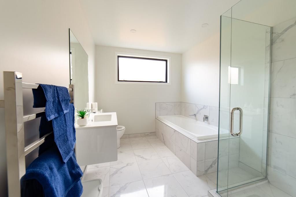 A modern bathroom with a glass-enclosed shower, a white sink, and a large mirror.