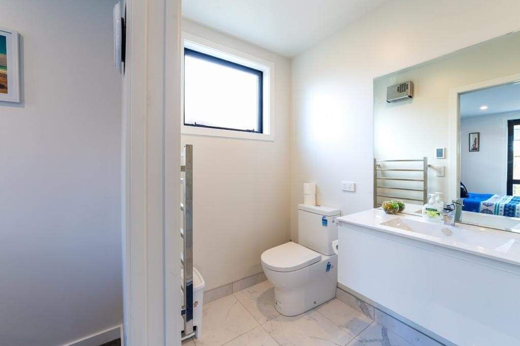Un baño moderno con inodoro, lavabo y espejo.