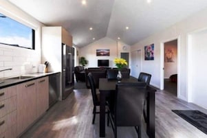 Una cocina moderna con zona de comedor, suelo de madera y un ventanal grande.