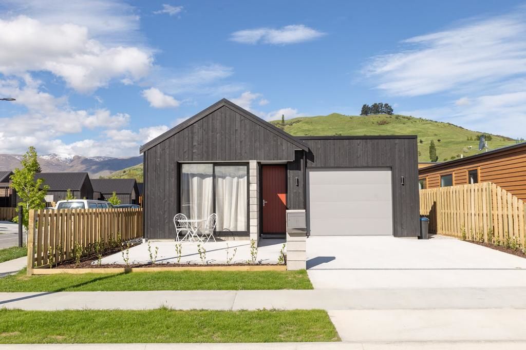 A modern two-story house with a garage, a fenced yard, and a clear view of the mountains in the background.