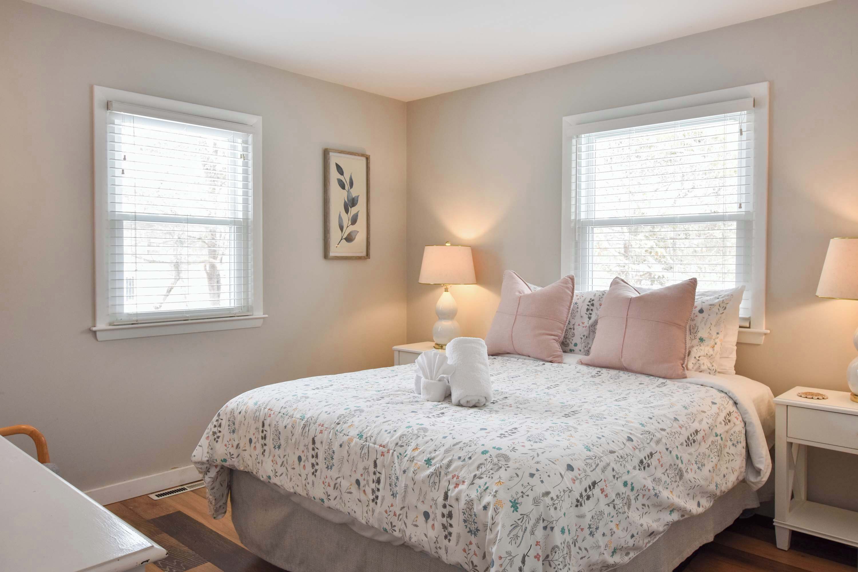A bedroom with a large bed, two bedside tables with lamps, and a window with blinds.