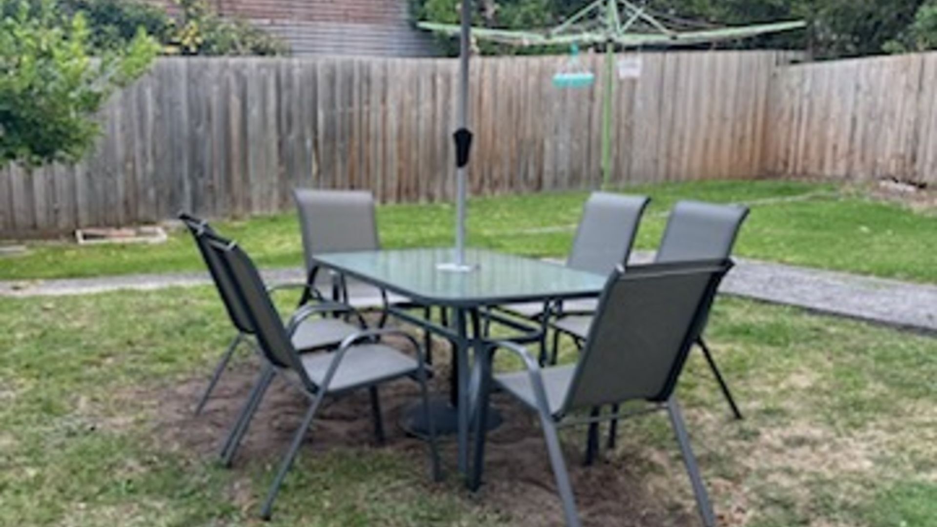 A round table with four chairs in a backyard setting.
