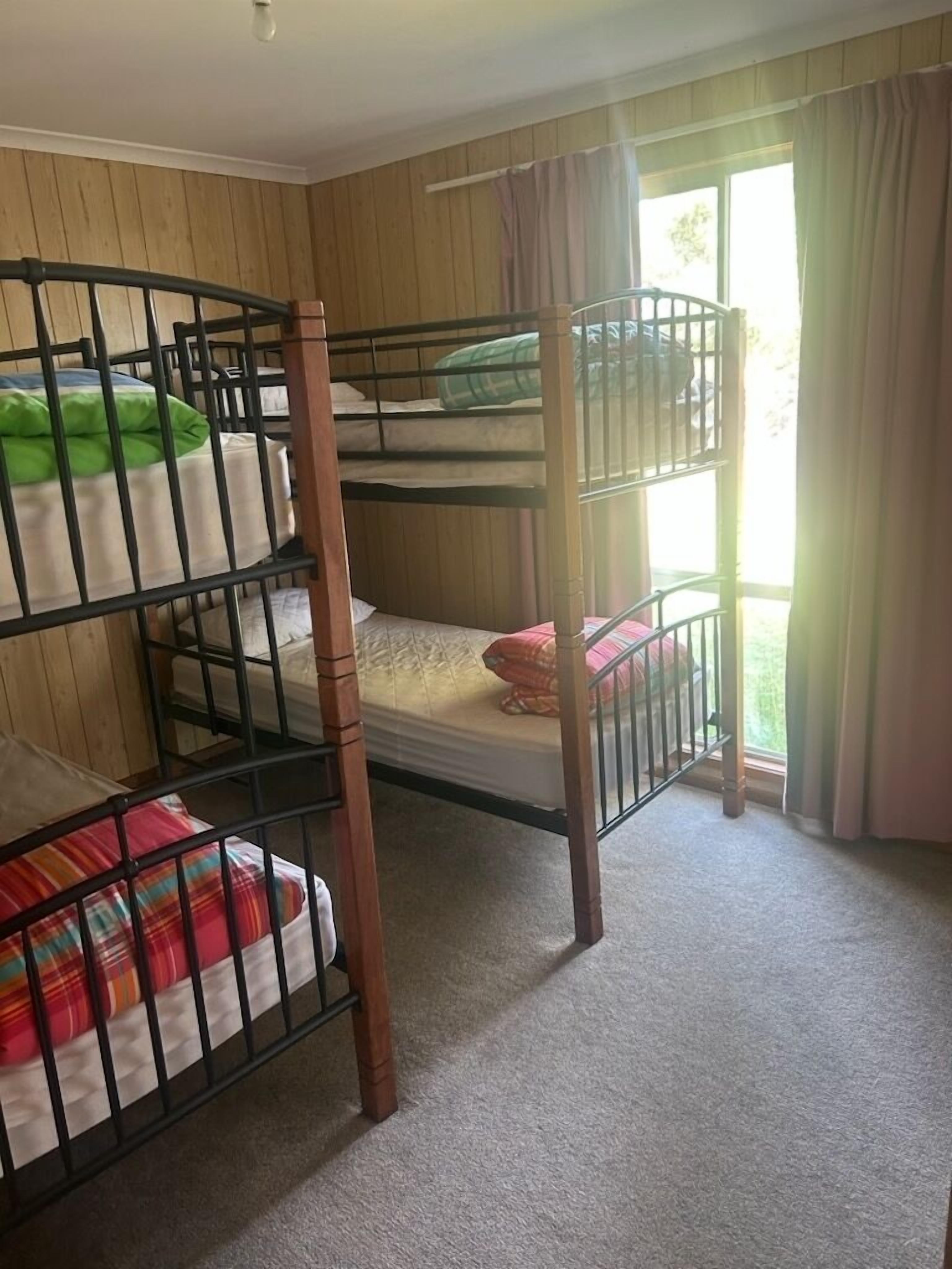 A bunk bed room with wooden walls and a carpeted floor.