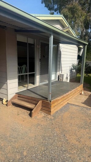 A house with a covered porch, a sliding glass door, and a small outdoor seating area.