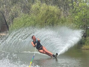 Iemand waterskiën op een rivier, met bomen op de achtergrond.