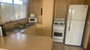 Una cocina compacta con lavamanos, microondas, estufa y refrigerador.