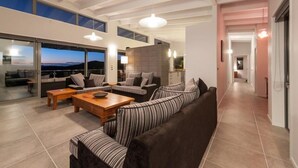 Un salon moderne avec un canapé, une table basse et une vue sur l’extérieur grâce à de grandes fenêtres.