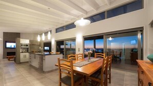 Une cuisine moderne avec un coin repas, de grandes fenêtres et une vue sur le coucher de soleil.