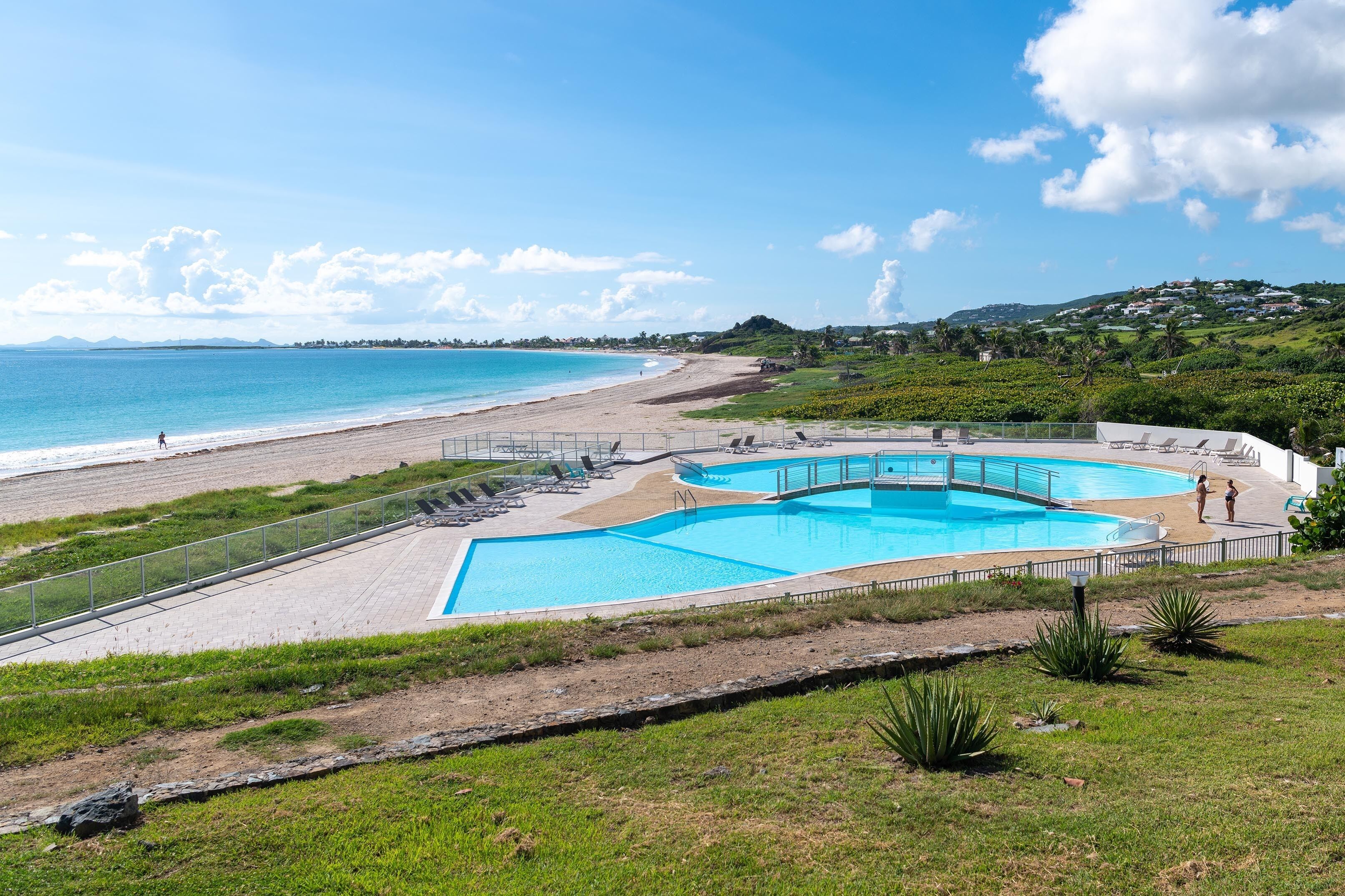 A beachside resort with a swimming pool, beach access, and a view of the ocean.