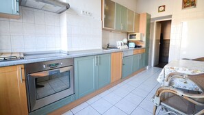 A kitchen with a built-in oven, a microwave, and a sink. There is a dining area with a table and chairs.