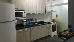 Une cuisine moderne avec des meubles de couleur bois clair, un réfrigérateur blanc, un four à micro-ondes et un évier.
