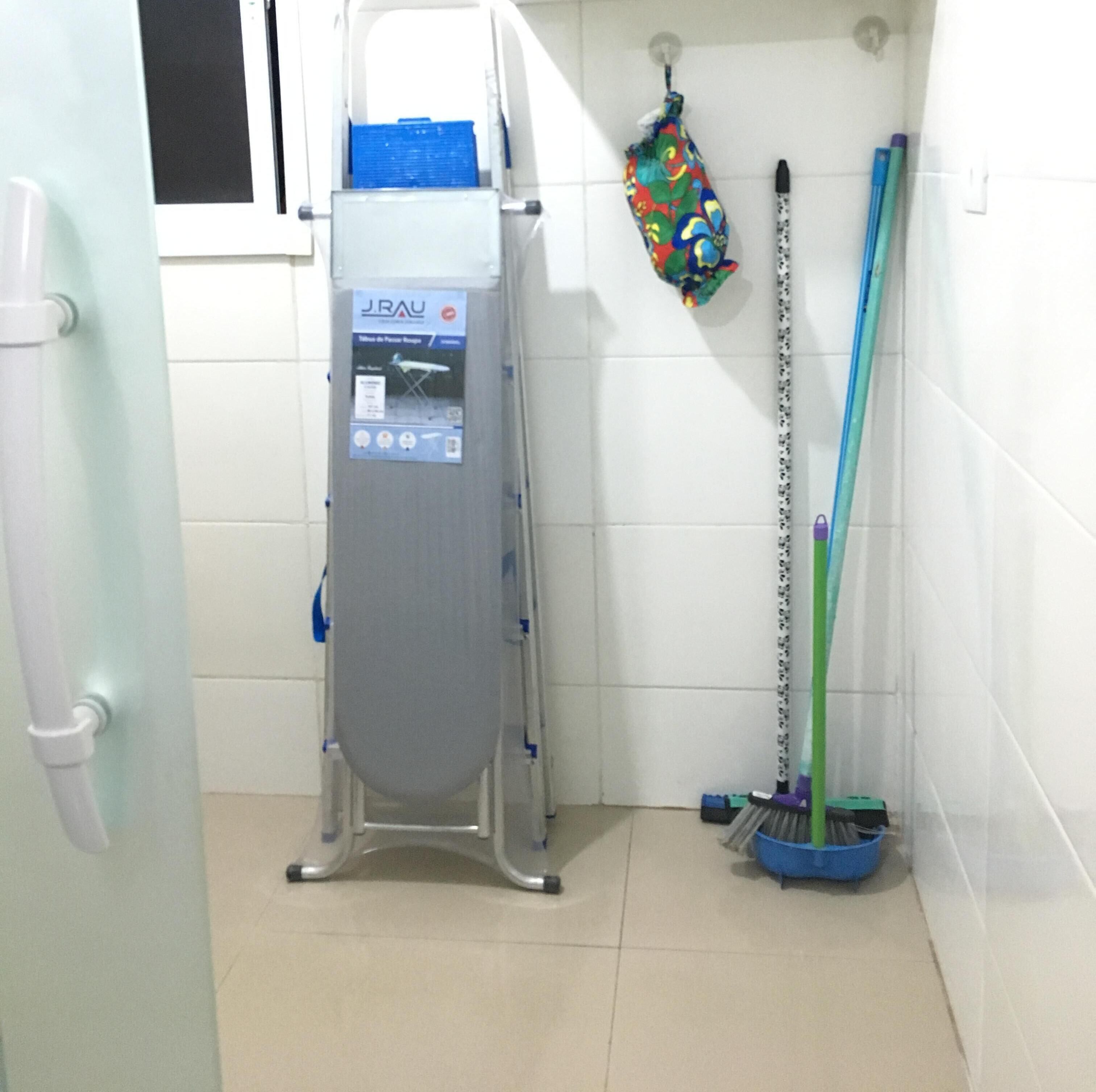 Un baño con una ducha portátil J.RAU, una toalla de mano colorida y una escoba.