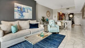 Un salon moderne avec un canapé, une table basse et des œuvres d’art. On y trouve également un coin repas avec une table et des chaises.