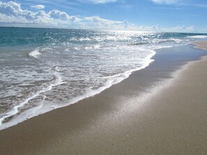 A beach with waves gently lapping onto the shore. - DOUBLE BALCONY IN BEAUTIFUL, MODERN ONE-BR CONDO! (Boynton Beach)