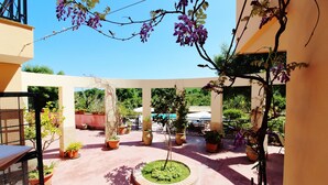 A courtyard with potted plants, a central circular garden, and a pergola with purple flowers. - Between Catania and Syracuse,countryside Villa  with private pool 1km from beach (Brucoli)