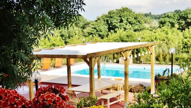 A wooden gazebo with a pool in the background, surrounded by lush greenery and vibrant flowers. - Between Catania and Syracuse,countryside Villa  with private pool 1km from beach (Brucoli)