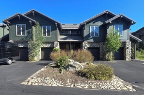 A two-story house with a stone foundation and a driveway.