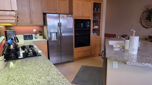 A kitchen with granite countertops, stainless steel appliances, wooden cabinets, and a built-in oven. - Snowcreek Resort Vacation Rental 990 (Mammoth Lakes)