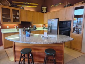 A kitchen with wooden cabinets, a granite countertop, a stainless steel refrigerator, and a built-in oven. - Snowcreek Resort Vacation Rental 990 (Mammoth Lakes)