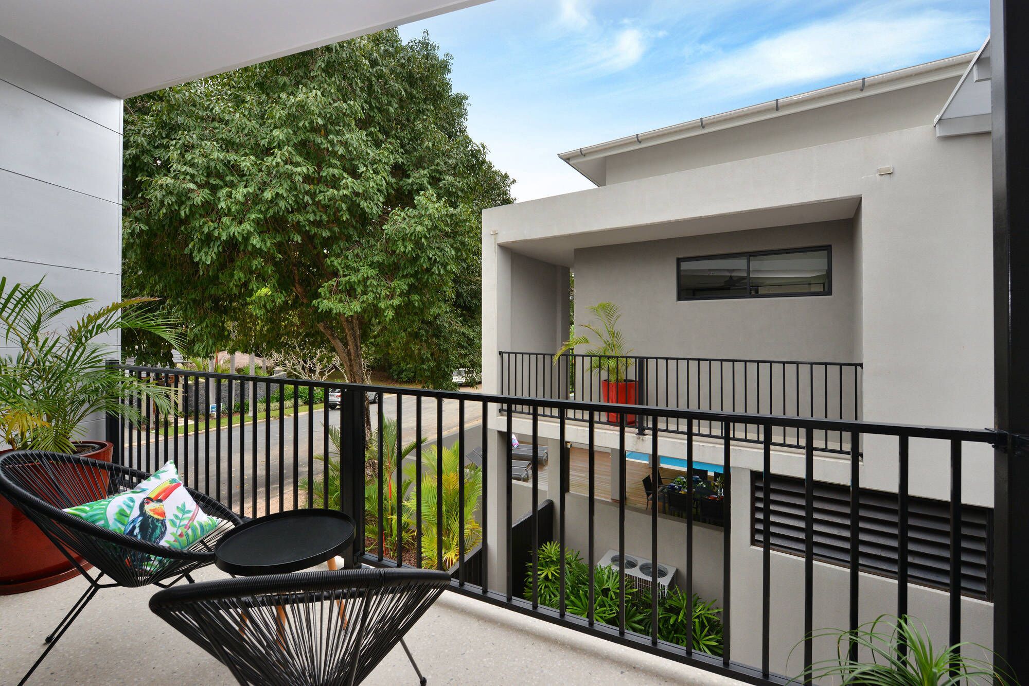 A balcony with a view of a tree and a modern building.