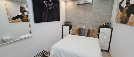 Un dormitorio moderno con una cama grande, un espejo y obras de arte en las paredes.
