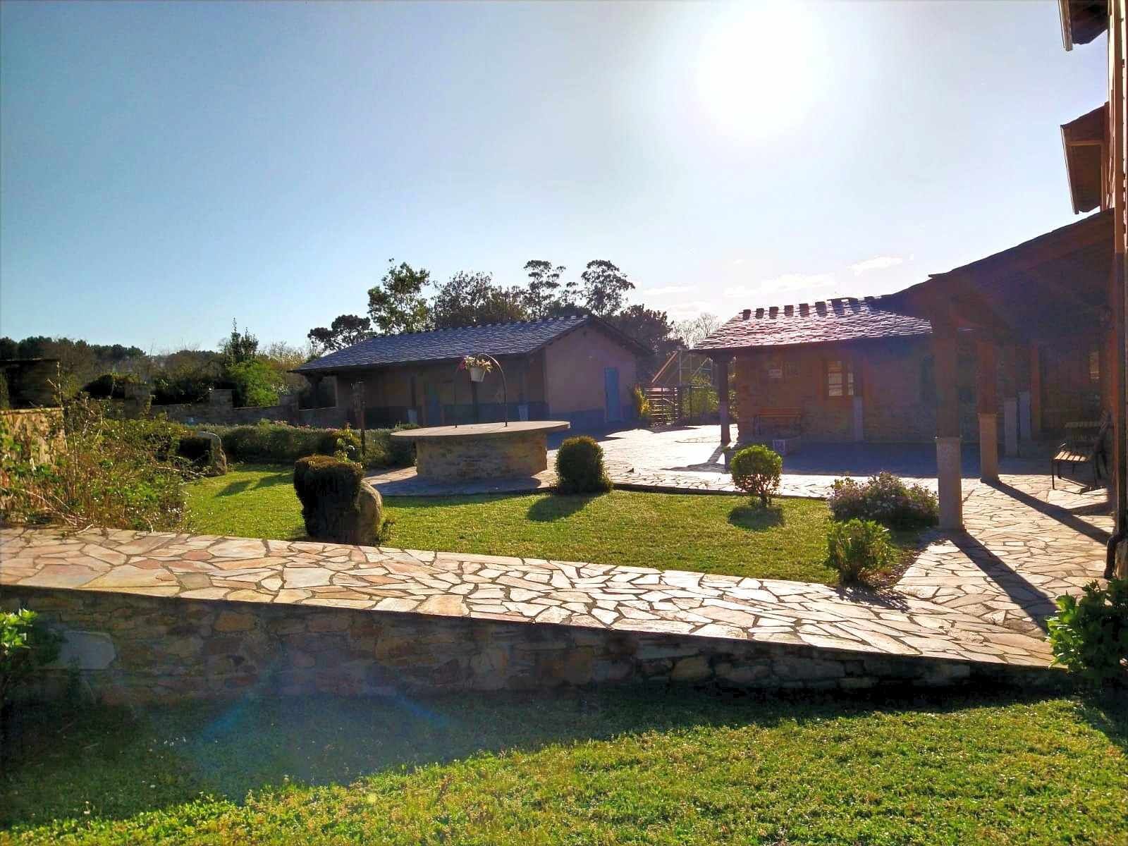 A courtyard with stone pathways, a small pool, and rustic buildings with tiled roofs.