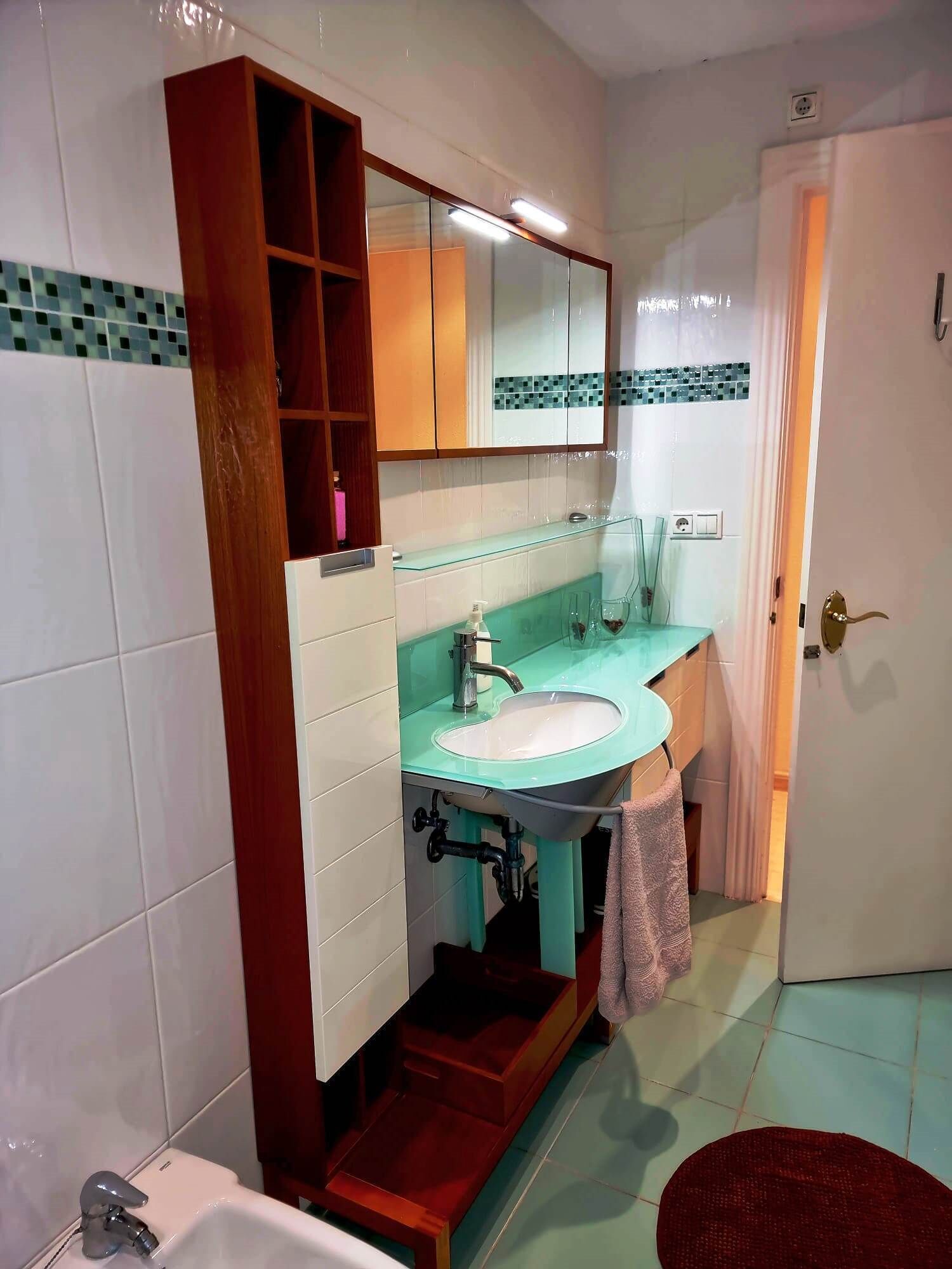 A bathroom with a double sink, a mirror, and a wooden cabinet.