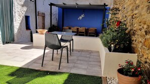 An outdoor patio with a table and chairs, a blue wall, and potted plants. - Rural house with garden and barbecue in the Moncayo area. (Bulbuente)