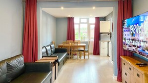 Una sala de estar con sofá, mesa de comedor, sillas y televisión.