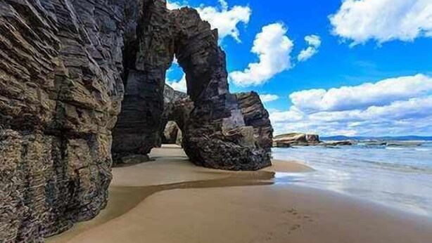 Una playa con grandes formaciones rocosas y un cielo despejado.