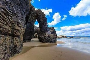 A beach with large rock formations and a clear sky.