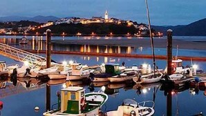 Un puerto deportivo con barcos amarrados, un muelle y una construcción con luces en la cima de una colina.