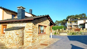 Un edificio de piedra con techo inclinado, una ventana de marco de madera y un camino pavimentado que conduce a una entrada con portón.
