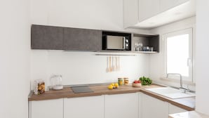Una cocina moderna con armarios blancos, encimera de madera, microondas integrado y una ventana sobre el fregadero.