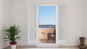 Un balcón con vista al mar, una silla de mimbre y una mesa con bebidas.