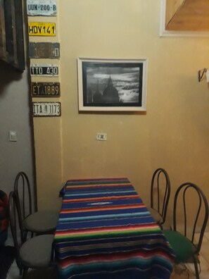 Ein Zimmer mit einem Tisch, Stühlen, einem gerahmten Bild und Wände mit Autokennzeichen.