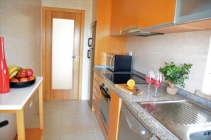 A kitchen with a microwave, toaster, and a sink with a cutting board. - Penthouse Apartment With Communal Pool & Spectacular Lagoon Views. (Fuseta)