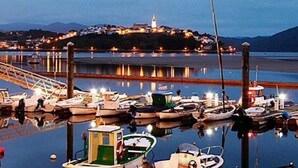 A marina with boats docked, a lighthouse in the background, and a bridge leading to the shore. - Apartment 2: With porch, pool and garden (Tapia De Casariego)