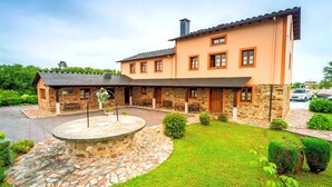 A two-story house with a stone facade, a stone patio, and a well-maintained lawn. - Apartment 2: With porch, pool and garden (Tapia De Casariego)
