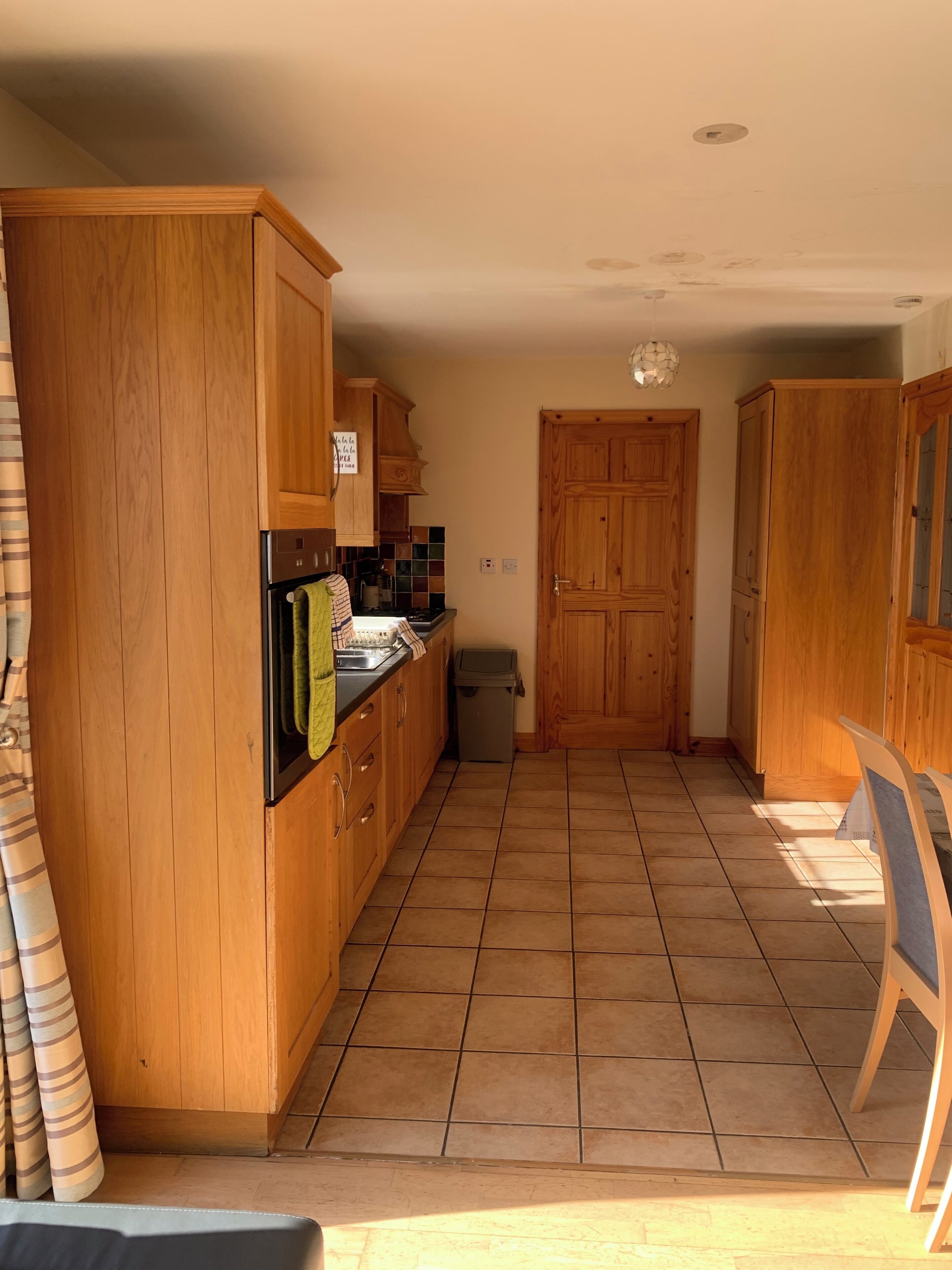 A kitchen with wooden cabinets, a tiled floor, and a view of the dining area.