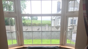 Ein schwarzes Ledersofa mit Kissen in einer Ecke eines Raumes mit großen Fenstern.